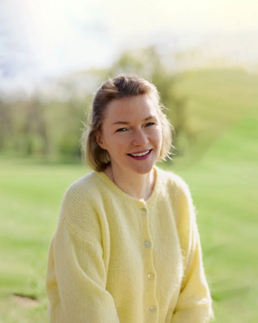 Birgit Kappes, Psychologin und Lifecoach in Hamburg, lächelnd in gelber Strickjacke im Park
